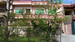 Edificio a due piani con facciata rossa e bianca, un balcone al piano superiore e una motocicletta parcheggiata davanti.