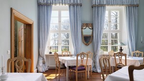 Ein Esszimmer mit Holzsesseln, einem Tisch und einem großen Spiegel an der Wand.