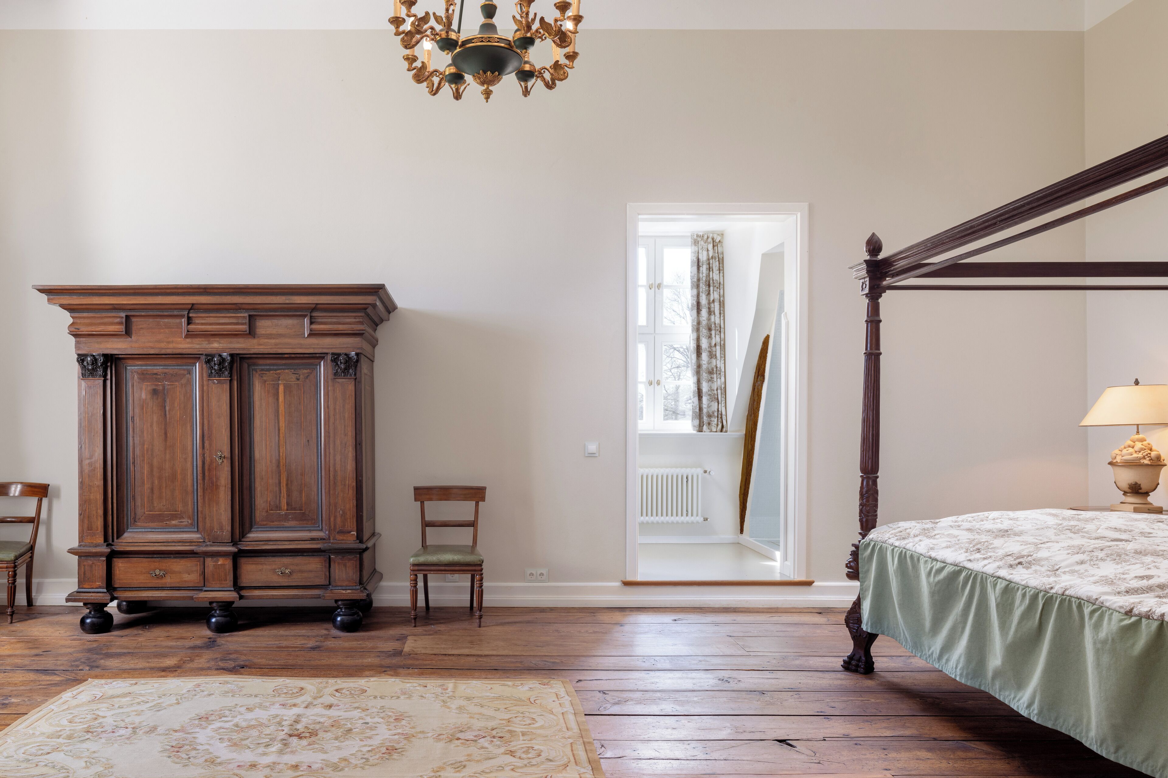 Un dormitorio con una cama con dosel, un armario de madera y un candelabro.
