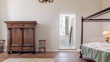 Un dormitorio con una cama con dosel, un armario de madera y un candelabro.