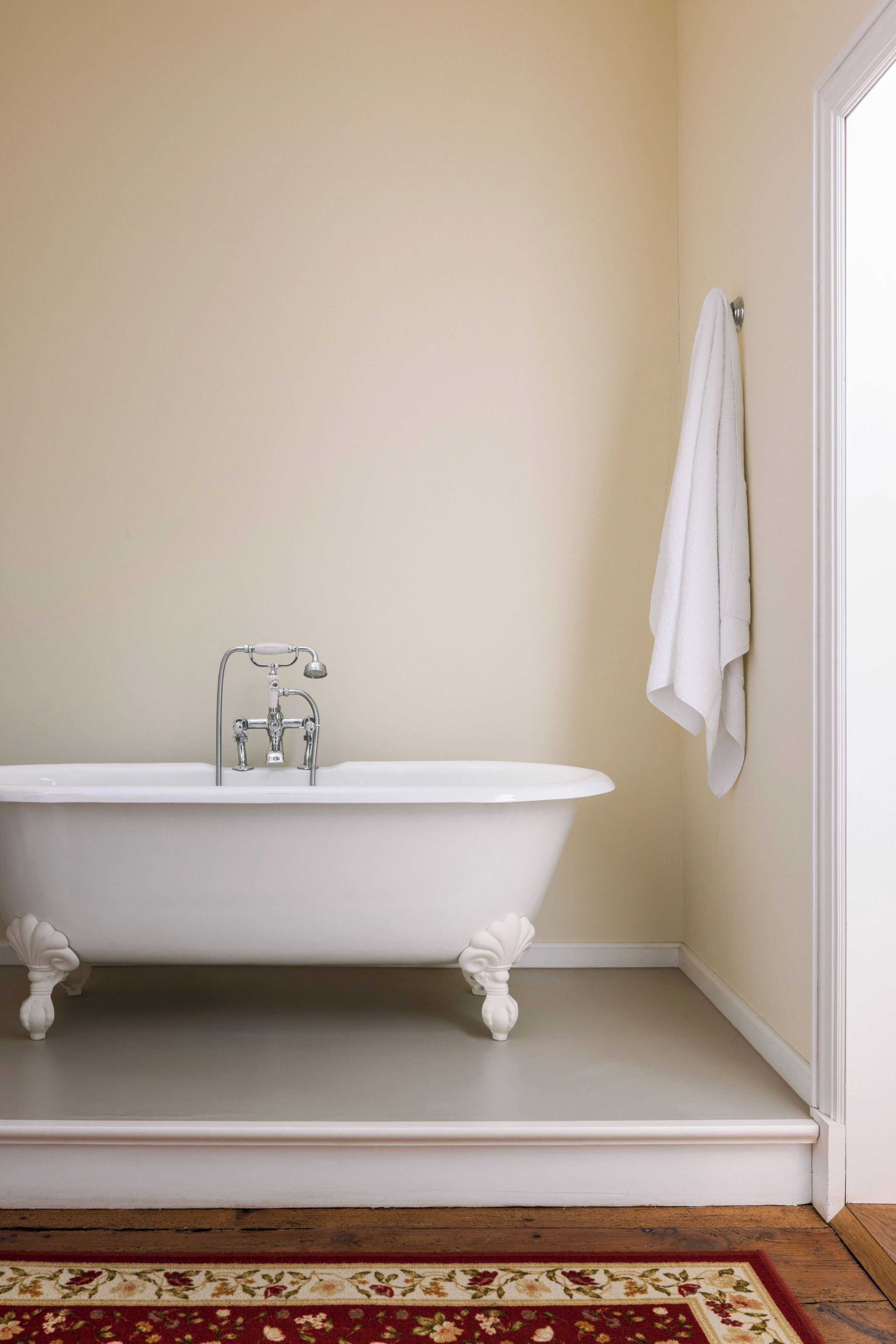 Een badkamer met een freestanding badkuip, een toilet en een handdoek aan de muur.