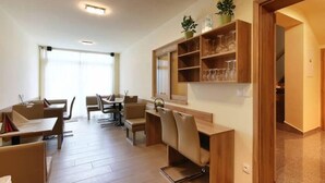 A modern hotel room with a dining area, a sofa, and a shelf with glassware. - Penzion Vanessa (Brno)