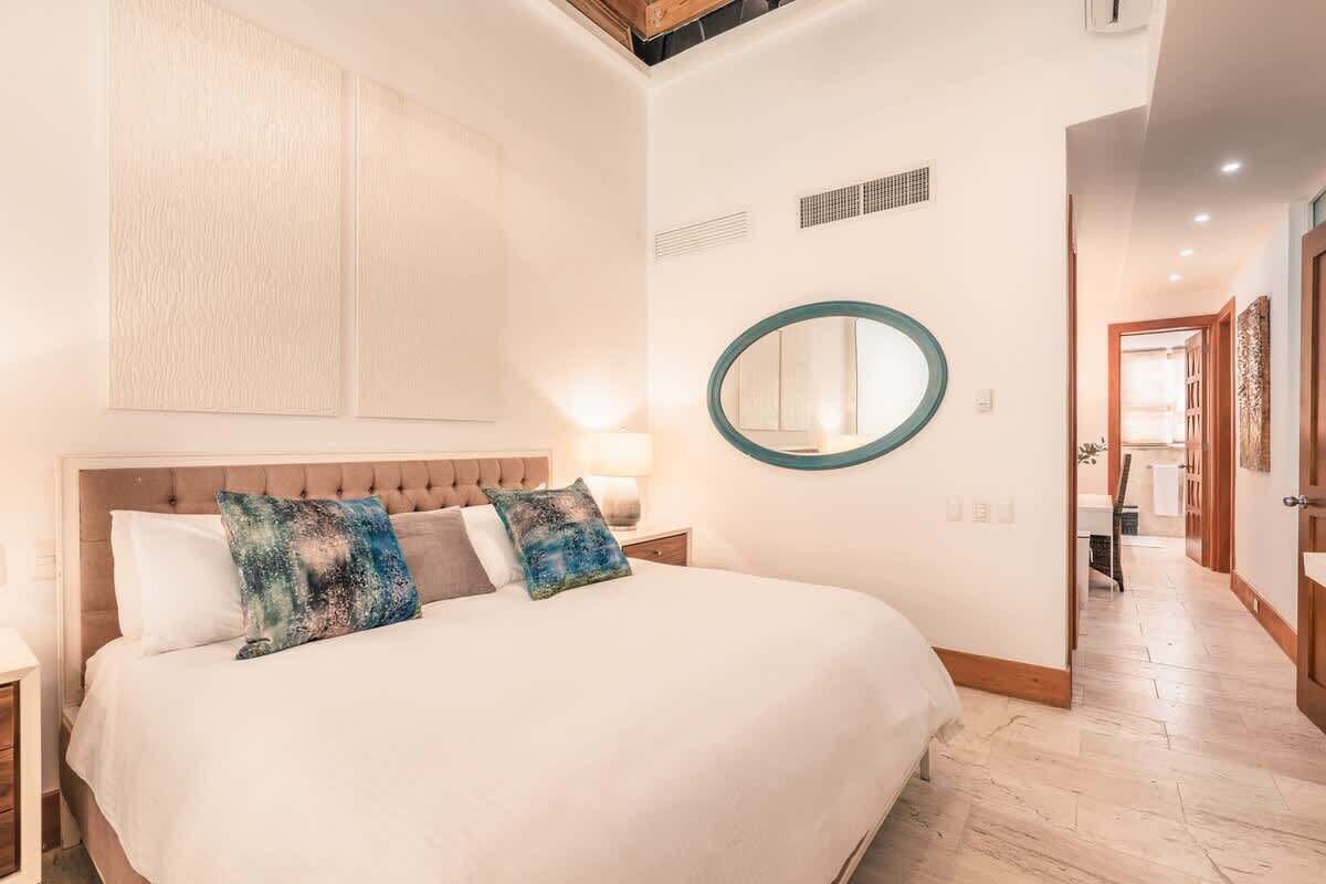 Ein Schlafzimmer mit einem großen Bett, einem runden Spiegel und einem hölzernen Kopfteil.