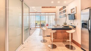 A modern kitchen with a large island, bar stools, and a stainless steel refrigerator. - Luxury Golf View Apartment near Casa de Campo (Casa De Campo)