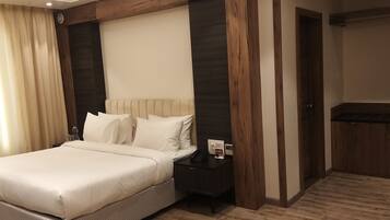 A hotel room with a large bed, a bedside table with a phone and a photo frame, and a wooden accent wall.