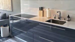 A modern kitchen with a large island, stainless steel appliances, and a minimalist design. - Garden Jewel Design Apartment (Minusio)