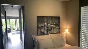 A bedroom with a bed, a nightstand, a wall-mounted lamp, and a painting. - Garden Jewel Design Apartment (Minusio)
