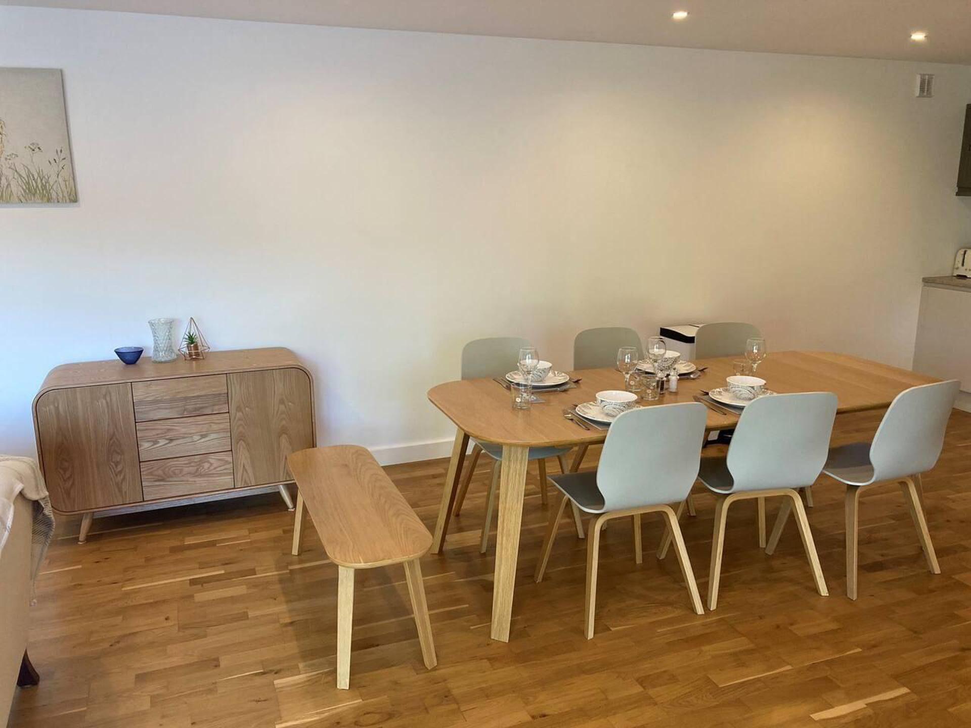 Comedor con una mesa de madera dispuesta para seis personas, rodeado de seis sillas.