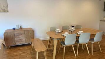 Comedor con una mesa de madera dispuesta para seis personas, rodeado de seis sillas.