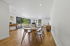 A spacious dining area with a wooden table and chairs, large windows, and a view of greenery outside. - Countryside Annex- Sleeps 2, Free Parking & Garden (Canterbury)