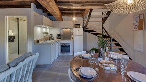 Eine moderne Küche mit Kochinsel, ein Essbereich mit Holztisch, gedeckt für eine Mahlzeit, und eine Treppe, die zu einer weiteren Ebene führt.