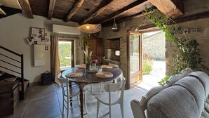 Ein rustikaler Essbereich mit Holztisch und -stühlen, einer Hängelampe und Blick ins Freie.