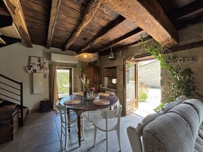 Un comedor rústico con una mesa y sillas de madera, una lámpara colgante y vistas al exterior.