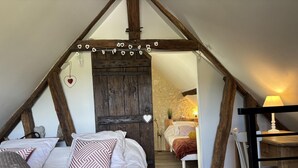 Ein rustikales Schlafzimmer mit freiliegenden Holzbalken, einem Schlafbett auf Hochbett und einer gemütlichen Atmosphäre.