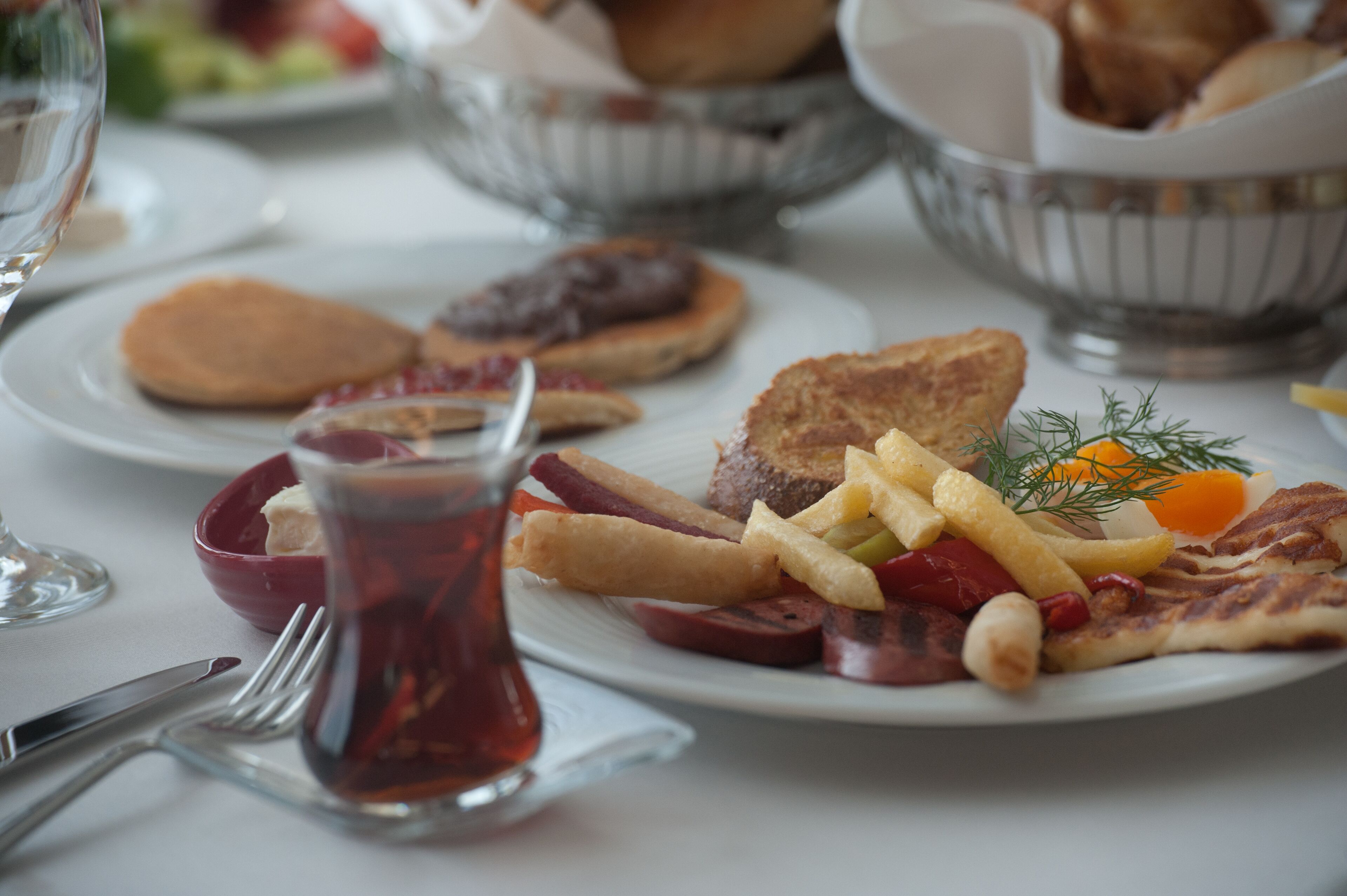 A dining table with plates of food, including toast, fries, and a drink.