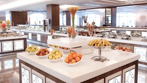 A buffet area with various fruits and dishes, including bowls of apples, oranges, and bananas, and a decorative vase. - Alusso Thermal Hotel & Spa (Afyonkarahisar)
