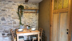 A dining area with a stone wall, wooden table, and chairs. - Small welcoming house in a farmhouse. (Parisot)