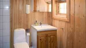 Ein Badezimmer aus Holz mit Toilette, Waschbecken und Schränken.