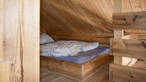 Ein kleines Schlafzimmer im Dachgeschoss, mit Holzboden, einem Einzelbett und einem Holz-Kopfteil sowie einer schrägen Decke.