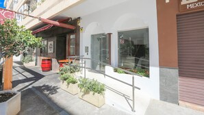 A building with a storefront, outdoor seating area, and a staircase leading to an entrance. - Alcazaba Square Central Beach (La Herradura)