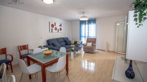 Un salon moderne comprenant un canapé, une table à manger, des chaises et une table basse en verre.