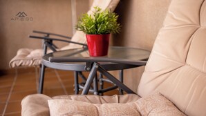 Un espace extérieur moderne, aménagé avec des sièges confortables, une petite table et un pot de fleurs.
