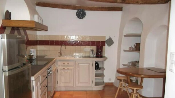A kitchen with a refrigerator, stove, sink, and wooden stools. - Charming village house (Buis-les-Baronnies)