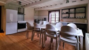 Una cocina con electrodomésticos blancos, una mesa de comedor con sillas y una ventana con vistas.