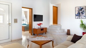 Ein Wohnzimmer mit einer Couch, einem Couchtisch, einem Fernseher und einer Treppe, die zu einer oberen Etage führt.