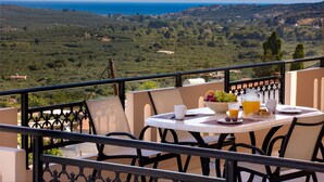 Ein Balkon mit Frühstückstisch, mit Blick auf eine Küstenlandschaft.