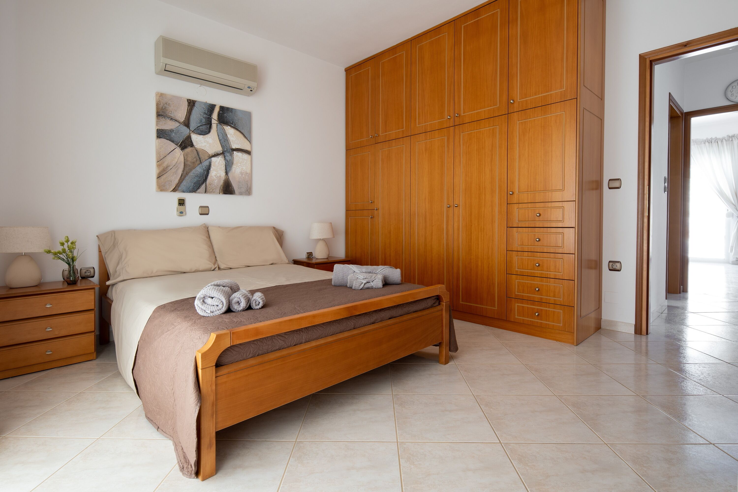Une chambre à coucher avec un lit en bois, une table de chevet, une armoire et un tableau accroché au mur.