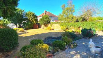 Enjoy a serene garden retreat with a swing set for kids, a stone pathway, and a small pond.