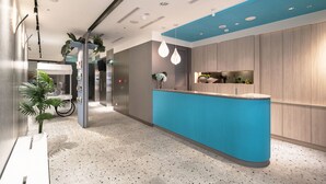 A modern reception area with a blue counter, a bicycle, and potted plants. - COMMA Boutique Hotel (Taipei)