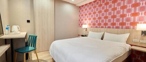 A hotel room with a bed, a desk with a chair, a water dispenser, and a patterned wall.