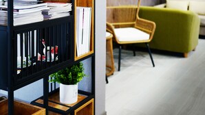 A modern interior with a black and wooden bookshelf, a green sofa, and a wicker chair. - COMMA Boutique Hotel (Taipei)
