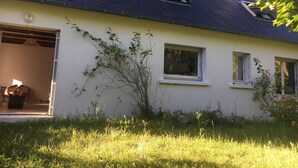 Ein Haus mit offener Garagentür, einem Fenster und einem kleinen Baum davor.