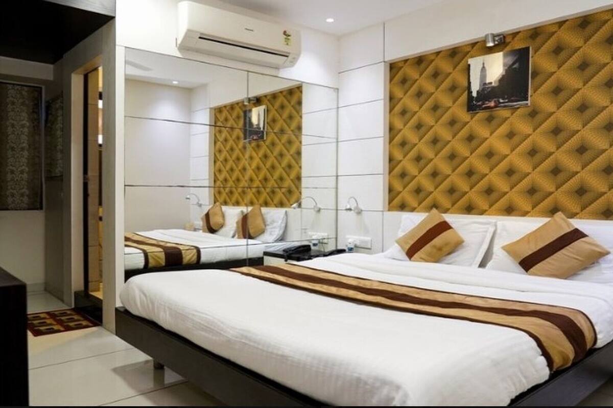 A hotel room with a large bed, a mirror, and a wall-mounted air conditioner.