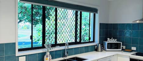 Eine moderne Küche mit Fenster, Spüle, Mikrowelle und Geschirrspüler.
