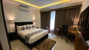 A modern hotel room with a large bed, bedside tables, a desk, and a chair. - Grand Mongolia Hotel (Mekhtar)