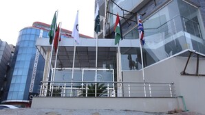 A modern building with multiple flags, including the UAE flag, and a glass facade. - Grand Mongolia Hotel (Mekhtar)