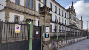A historic building with a gated entrance, a no parking sign, and a parking sign indicating a nearby parking area. - Hospedería San Froilan  (Lugo)