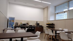 A modern classroom with white chairs, wooden tables, a whiteboard, and a window with blinds. - Hospedería San Froilan  (Lugo)