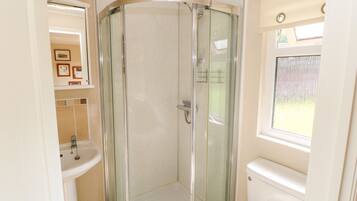 Un bagno con doccia vetro, lavandino e water.