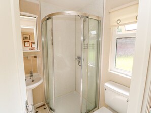Un baño con ducha acristalada, lavamanos e inodoro.