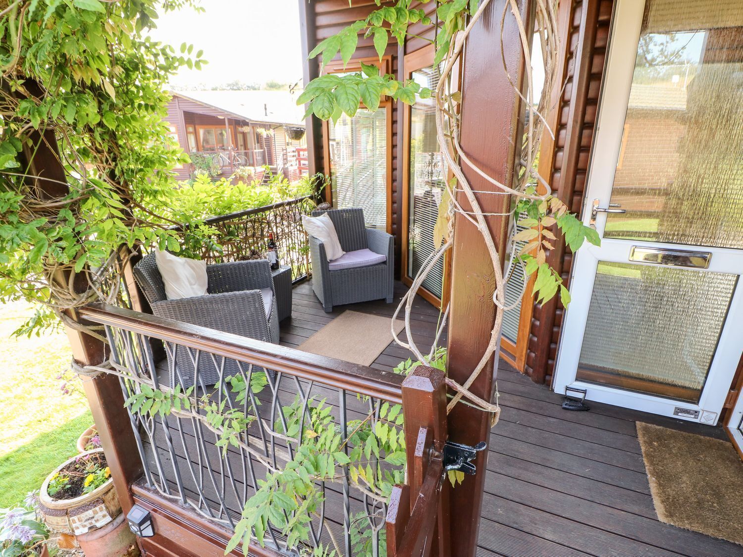 A wooden deck with wicker furniture, a glass door, and a potted plant.