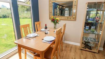 A dining area with a table set for four, a wine bottle, and a vase with flowers.