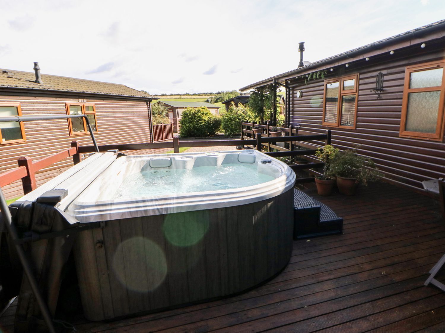 A hot tub on a wooden deck with a view of a house in the background.