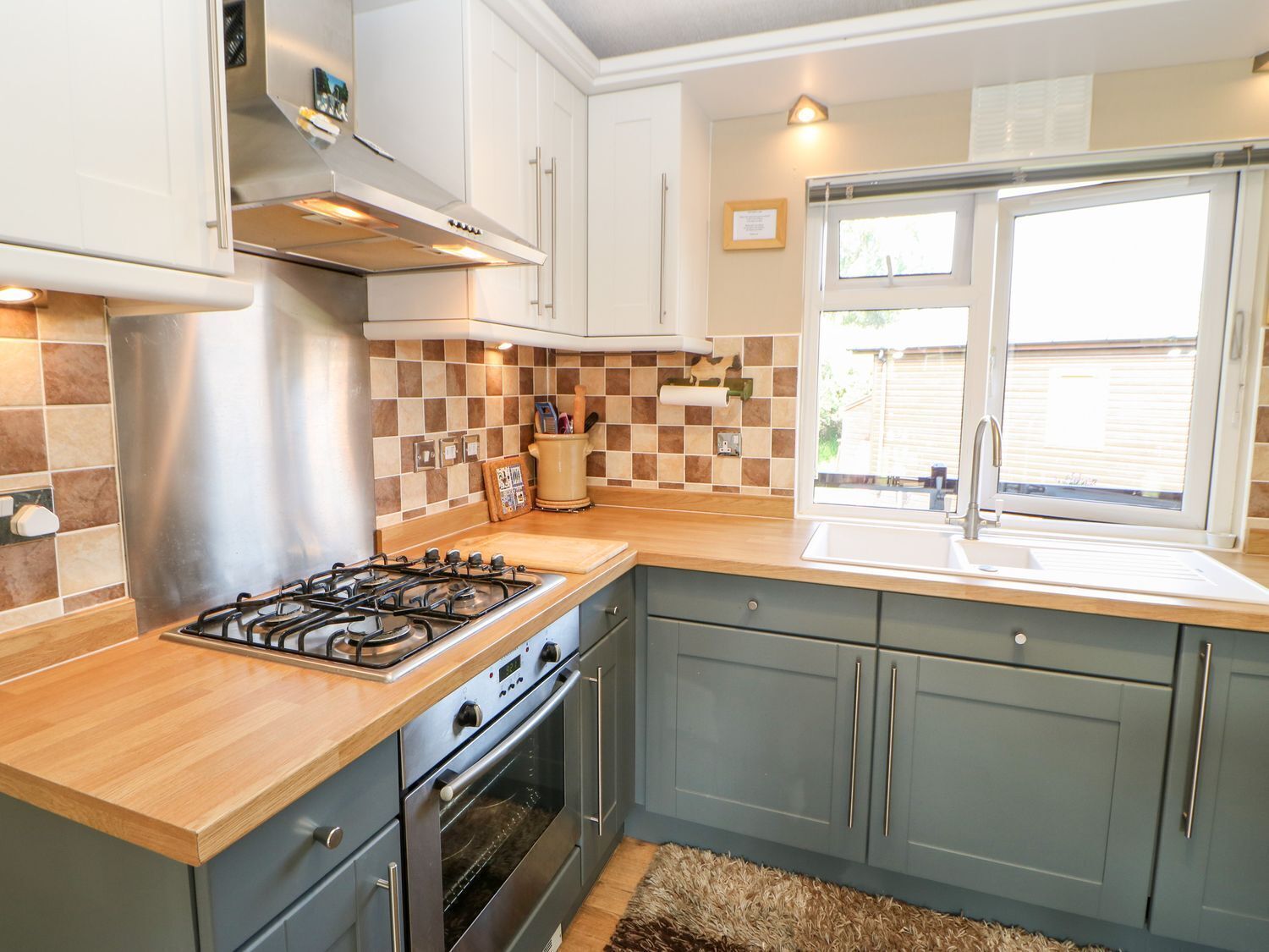 A modern kitchen with a gas stove, oven, and a window with a view of the outside.