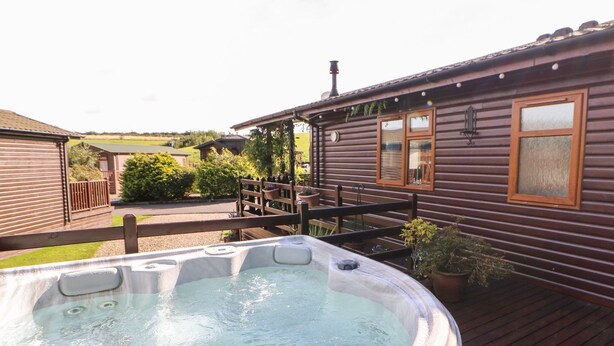 A hot tub in a wooden deck area with a house in the background. - 6 Badgers Retreat (Richmond)
