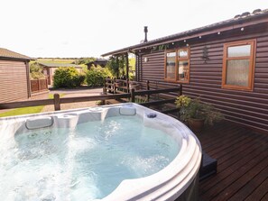 A hot tub in a wooden deck area with a house in the background. - 6 Badgers Retreat (Richmond)